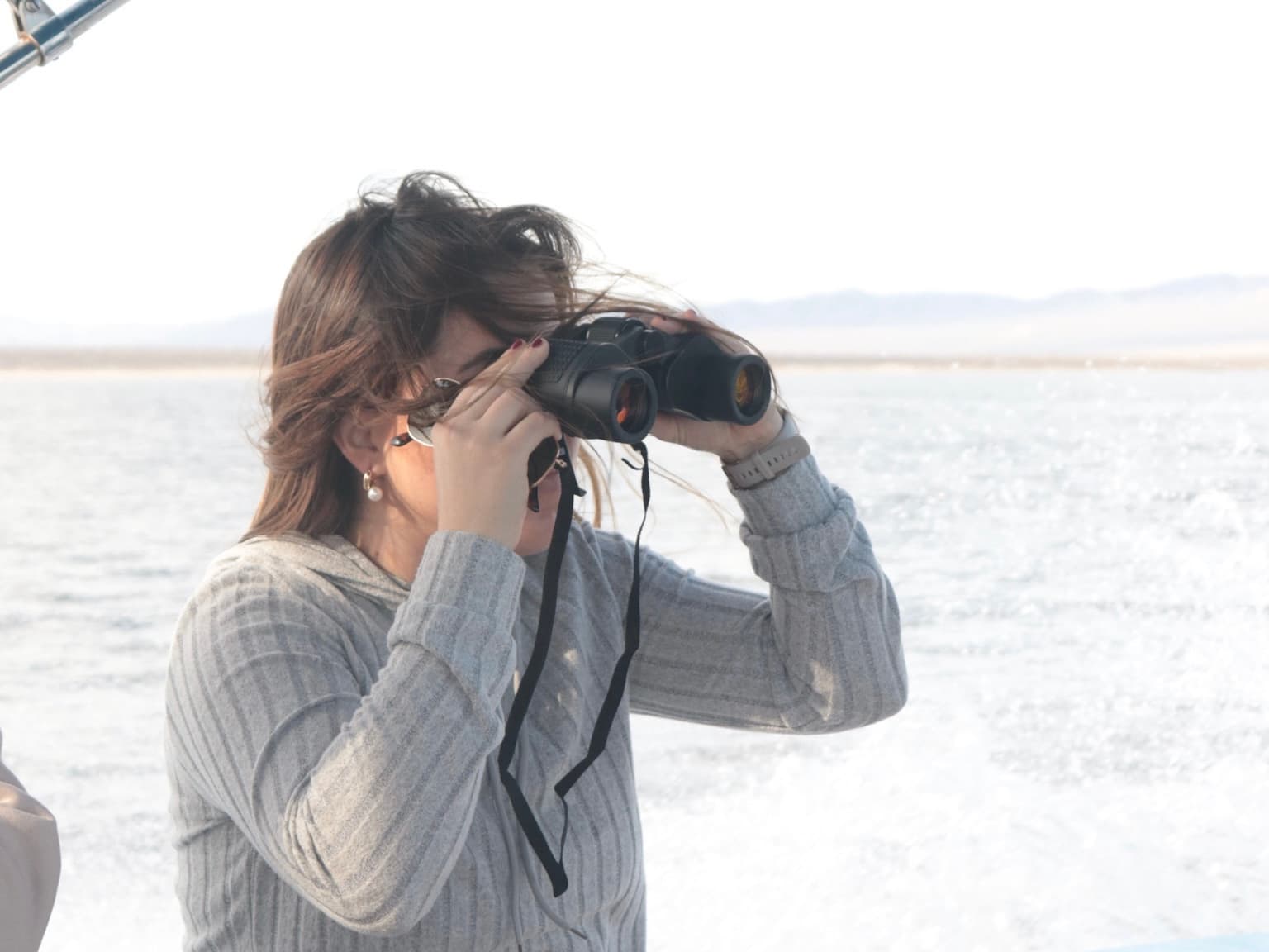 Guide with binoculars searching for wildlife from a panga in the Pacific
