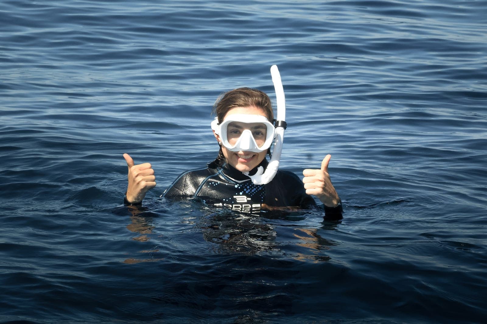 Traveler with snorkel giving a thumbs up in the sea